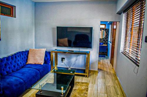 a living room with a blue couch and a tv at 1 Bedroom Apartment Oak Park Stays in Pietermaritzburg