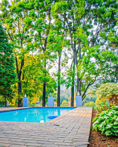 a swimming pool in a park with trees at 1 Bedroom Apartment Oak Park Stays in Pietermaritzburg