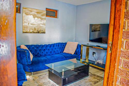 a living room with a blue couch and a tv at 1 Bedroom Apartment Oak Park Stays in Pietermaritzburg