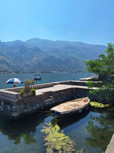 a boat in the water next to a stone wall at Old stone house Danka in Kotor