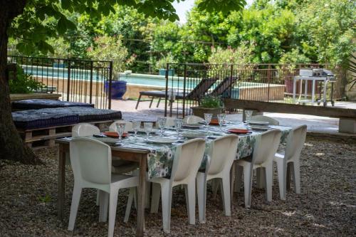 - une table avec des chaises blanches et une table avec des verres dans l'établissement Mas provençal 14 personnes - parking privé, au Thor