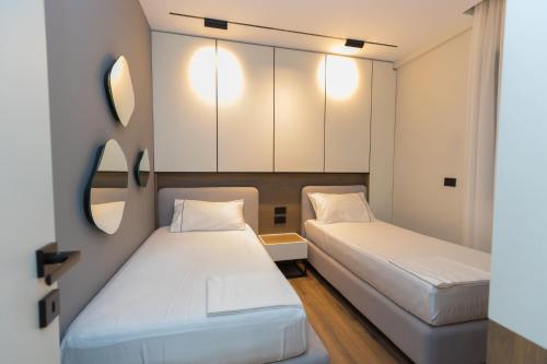 two beds in a small room with mirrors at Diora'S Hotel and Apartments in Vlorë