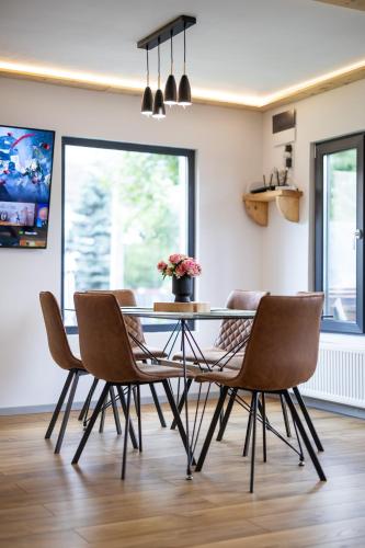 a dining room with a glass table and chairs at The Bear Chalet with Private Hot Tub in Buşteni