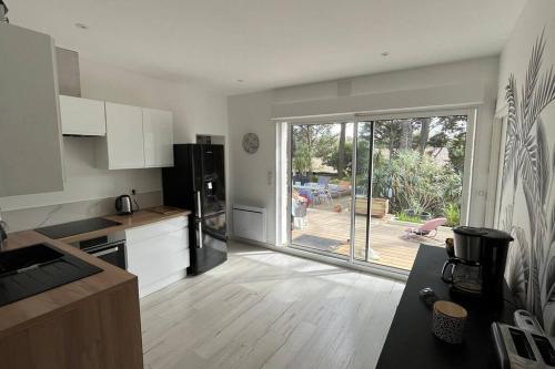 une cuisine avec une grande porte coulissante en verre donnant sur une cour. dans l'établissement Charmante villa au coeur du Cap Ferret, à Lège-Cap-Ferret