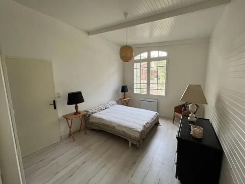 une chambre avec un lit et deux tables et une fenêtre dans l'établissement Charmante villa au coeur du Cap Ferret, à Lège-Cap-Ferret