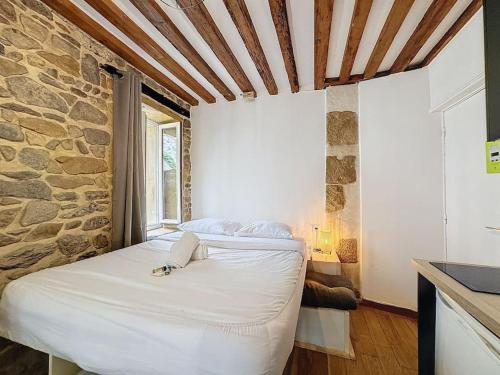 - une chambre avec un lit blanc et un mur en pierre dans l'établissement My home st barthelemy 1, à Lyon
