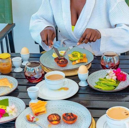 a woman sitting at a table with plates of food at The Kilimanjaro Villa in Moshi