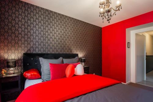 - une chambre rouge avec un lit et des oreillers rouges dans l'établissement Amour & Romance l Jacuzzi XXL l Table de massage, à Vigneux-sur-Seine