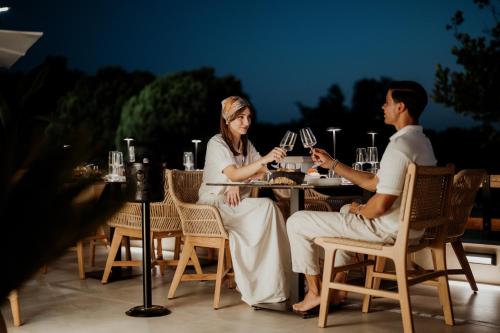 a man and woman sitting at a table with wine glasses at Kalani Residence in Keramotí