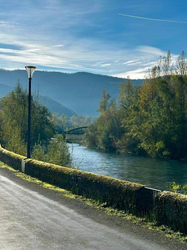 a road with a street light next to a river at La Cheminée - Chambres d'hôtes avec bar-restaurant in Tardets-Sorholus