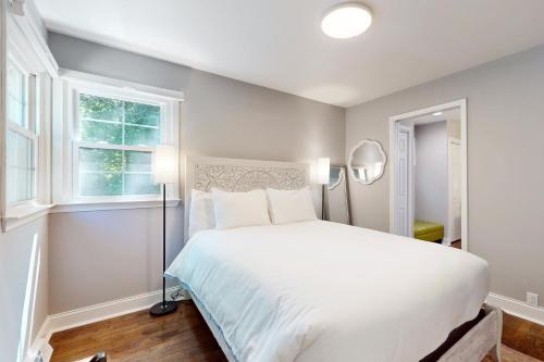 a bedroom with a white bed and two windows at Poolside Paradise in South Haven