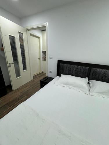 a bedroom with a large white bed with a black headboard at Apartament Drasa in Gjirokastër