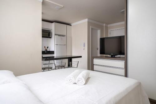 a bedroom with a white bed with two towels at Aptos a 2min da praia Balneário Camboriú/SC - EAC in Balneário Camboriú