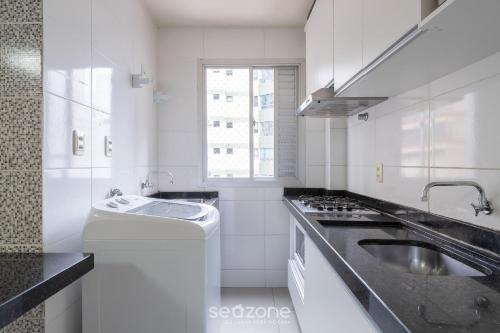 a white kitchen with a sink and a stove at Aptos a 2min da praia Balneário Camboriú/SC - EAC in Balneário Camboriú