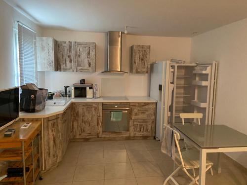 - une cuisine avec des placards en bois, une table et un réfrigérateur dans l'établissement Location mer les sablettes chez Huguette, à La Seyne-sur-Mer