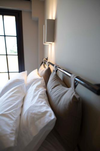 a bed with white pillows in a room with a window at RiZEΣ in Ouranoupoli