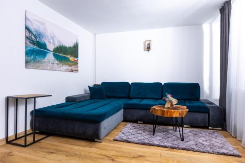 Una sala de estar con un sofá azul y una mesa. en The Bear House, en Buşteni