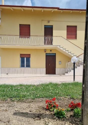 a yellow building with a balcony and some flowers at A casa di Vittorio - tra mare e colline in Montecosaro