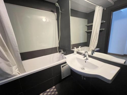 a bathroom with a sink and a mirror and a tub at Upground Residence Apartments in Bucharest
