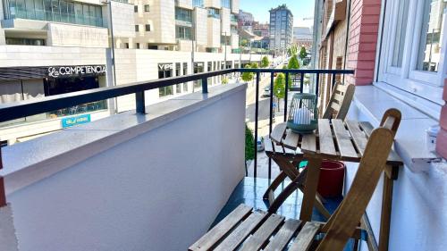 Un balcón con dos sillas de madera y una mesa encima. en Vetusta Nest, en Oviedo