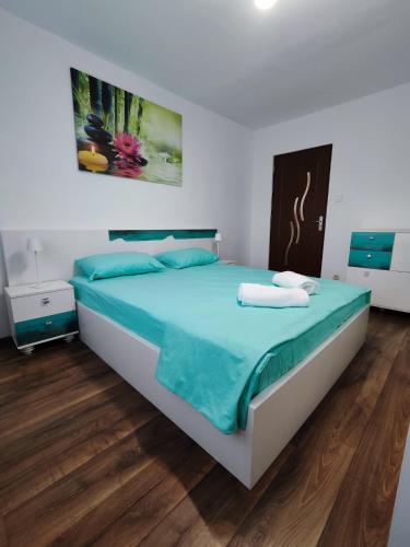 a bedroom with a large bed with blue sheets at Zen Apartament in Alba Iulia