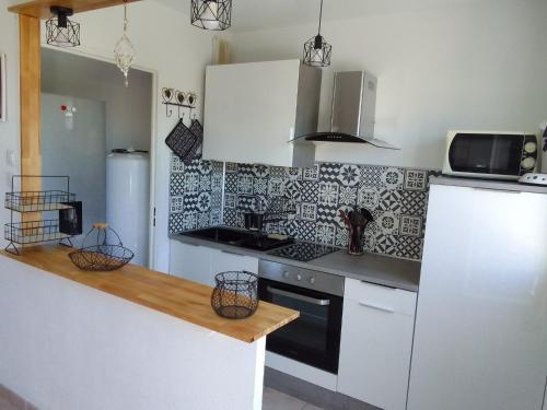 une cuisine avec des armoires blanches et un four à plaques de cuisson dans l'établissement Les baigneurs apt très calme 2 chambres 58 m2 parking privé et balcon, à Mers-les-Bains