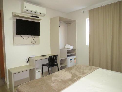 a hotel room with a bed and a desk and a tv at Sudoeste Hotel in Goiânia