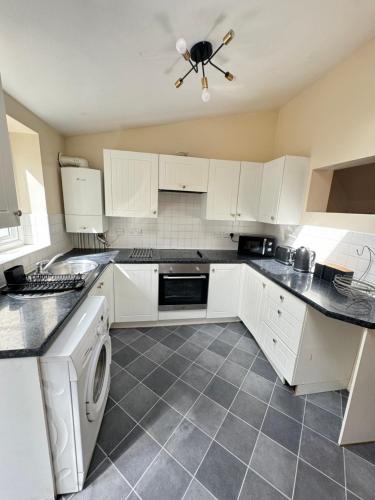 a kitchen with white cabinets and a washer and dryer at Shine Lodge in Kent