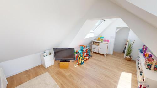a attic room with a tv and a desk at Le 44 - Maison familiale - Grand confort - 700m Plages in Dinard