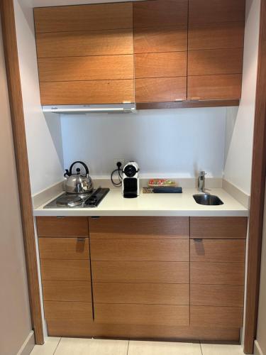 Elle comprend une petite cuisine avec des placards en bois et un évier. dans l'établissement Suite Supérieure 40 m2 Domaine du Golf St Endreol, 1 à 4 personnes, à La Motte