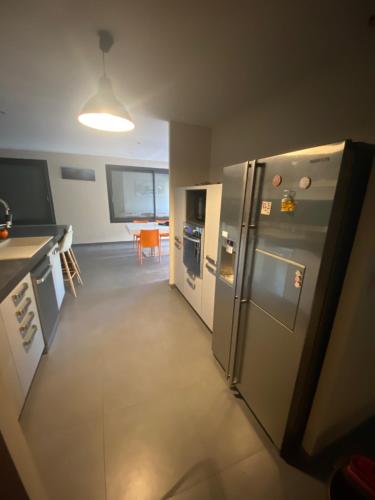 a kitchen with a stainless steel refrigerator and a table at Rev'ôthijol Vacances in Saint Alban Auriolles