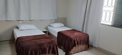 two beds in a small room with a window at Sudoeste Hotel in Goiânia