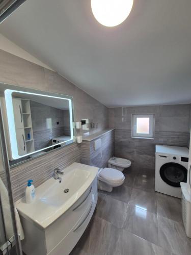 a bathroom with a sink and a toilet and a mirror at Apartment Donata in Privlaka