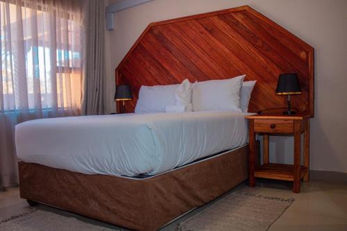 a bedroom with a large bed with a wooden headboard at The Chobe Inn in Kasane