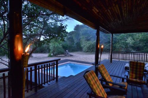 Umthiba Bush Lodge في KwaNibela: شرفة مع كرسيين ومسبح