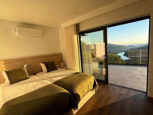 a bedroom with a bed and a large glass window at Encosta do Gerês Village in Ventosa