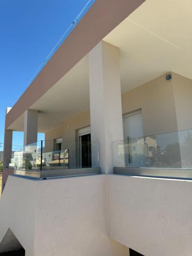 a house with large windows and a balcony at PUERTO VILLA, Best Location in Porto Rafti in Porto Rafti