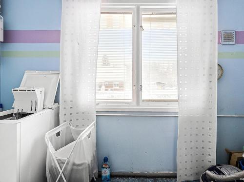 a kitchen with a window and a white curtain at Stuga Ani in Svartå