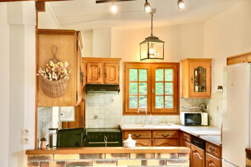 une cuisine avec des armoires en bois et un panier de fleurs dans l'établissement Riverside - Domaine 2 Maisons - Parc 1 hectare - Pont L'Eveque Deauville Normandie, à Le Mesnil-sur-Blangy