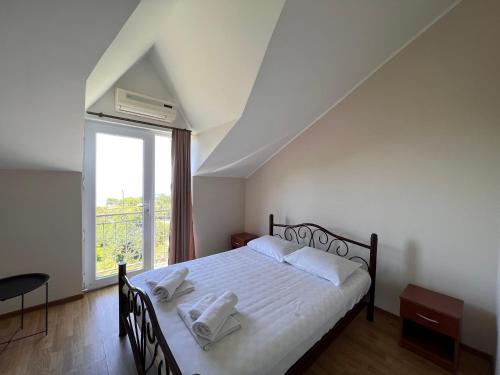 a bedroom with a bed with white sheets and a window at Green Garden Hotel in Makhinjauri