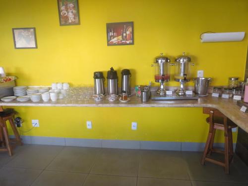 a kitchen with a yellow wall with a counter at Sudoeste Hotel in Goiânia