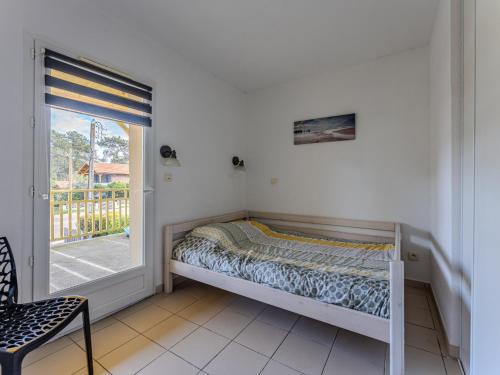 Ce lit se trouve dans un dortoir doté d'une fenêtre et d'une chaise. dans l'établissement Appartement Confortable Proche Océan avec Parking et Terrasse - 7 Pers - FR-1-521-244, à Biscarrosse