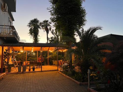 a patio with a table and chairs and palm trees at Green Garden Hotel in Makhinjauri