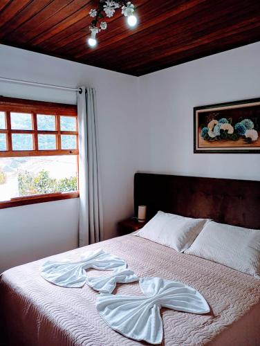 a bedroom with a bed with a robe on it at Chalé Château do Luí in Monte Verde