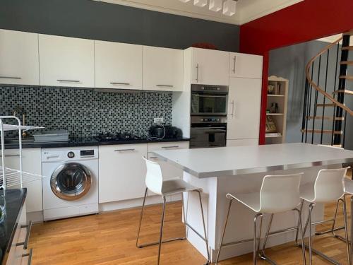 une cuisine avec des placards blancs et un comptoir blanc dans l'établissement Maison de la cigale enchantée, à La GrandʼCombe