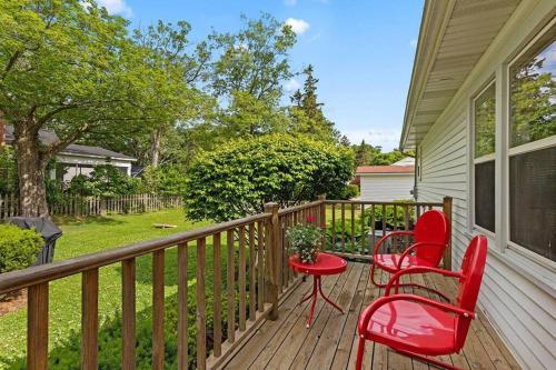 a deck with two red chairs and a table at 2min walk downtown-Pet Friendly-Offstreet Parking in Saugatuck