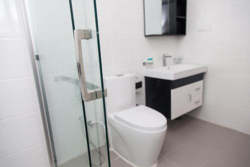 a white bathroom with a toilet and a sink at Beach Front Easy Living in Karagampitiya