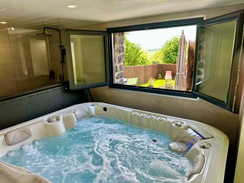 a jacuzzi tub in a room with a window at Maison Campagne SPA, Sauna, cinéma, jardin in Valuéjols