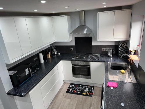 a kitchen with white cabinets and black counter tops at Affluent Living Property perfect for contractors and individuals in Wigan