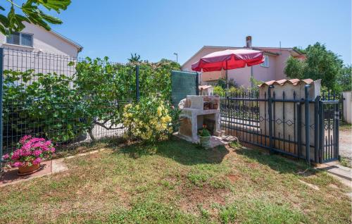 a fence with an umbrella next to a yard at Apartment Betiga Xiii in Barbariga